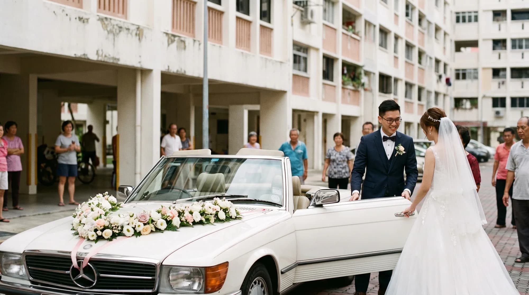 A white vintage convertible bridal car decorated with fresh flowers on the bonnet parked outside an HDB block in Singapore