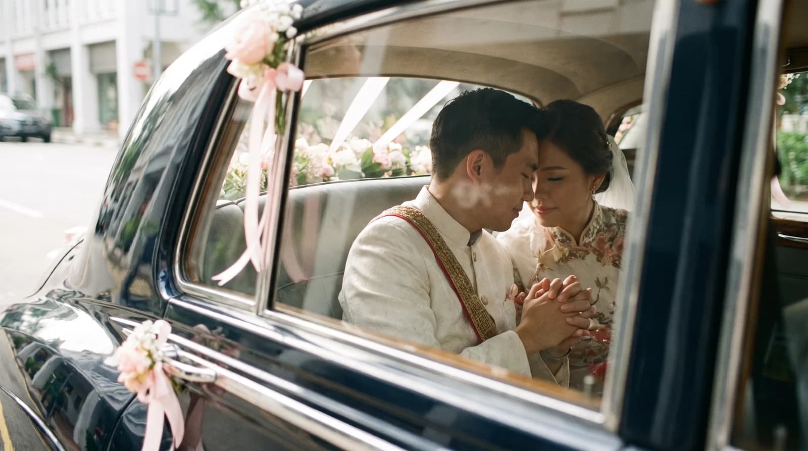 A couple sitting in the back seat of a decorated bridal car holding hands