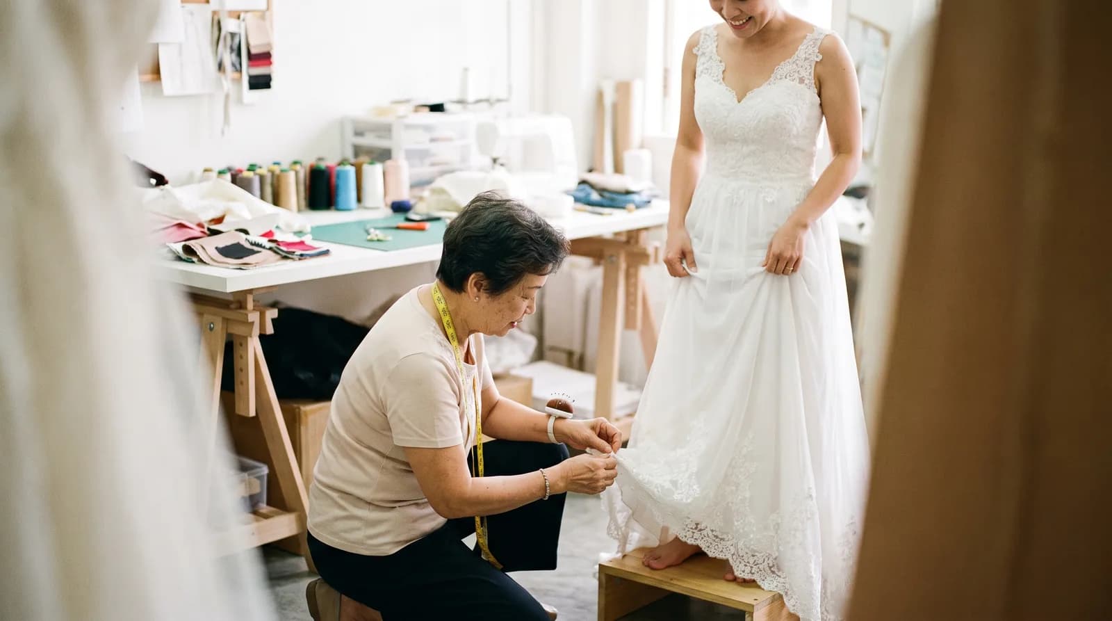 A seamstress pinning the hem of a wedding gown at a fitting