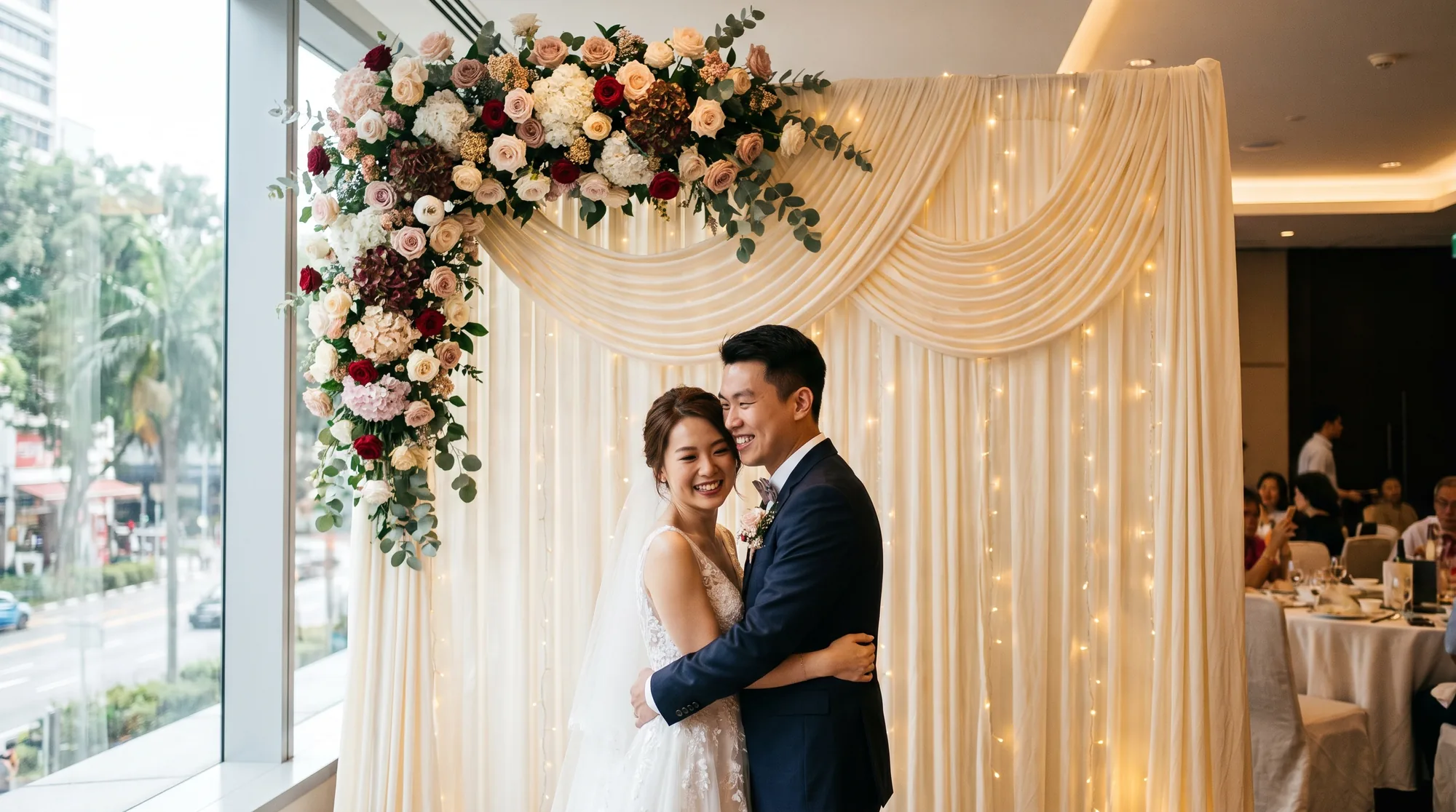 A romantic floral arch and pleated fabric backdrop styled for a wedding in a Singapore hotel function room
